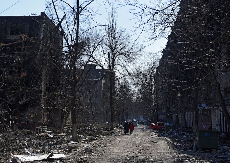 Residents walk between damaged residential buildings in Mariupol. Reuters