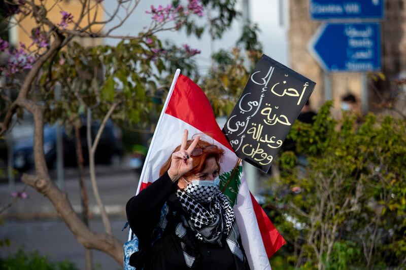 A protester holds a placard with Arabic that reads: "I yearn for my mother's freedom, my mother's justice and my mother's nation," as she participates in a march against the political leadership they blame for the economic, financial crisis and 4 Aug. Beirut blast, in Beirut. AP Photo