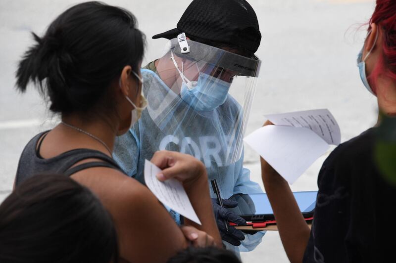 A testing centre worker collects information from people waiting in line at a walk-in coronavirus testing location in Los Angeles, California. AFP