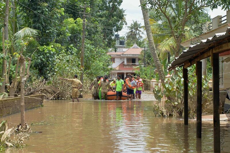 Kerala and Tamil Nadu Fire Force personnel transport children and elderly people in a dinghy through flood waters during a rescue operation in Annamanada village in Thrissur District, in Kerala, on August 19, 2018. AFP