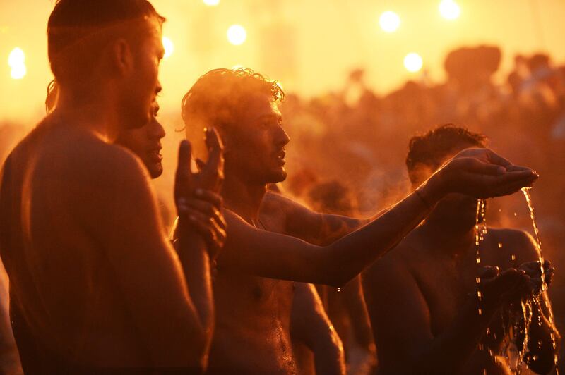 Hindu men pray as they bathe in the waters of the Sangham or the confluence of the the Yamuna and Ganges rivers during the Kumbh Mela in Allahabad on January 14, 2013. Hundreds of thousands of Hindu pilgrims led by naked, ash-covered holy men streamed into the sacred river Ganges on Monday at the start of the world's biggest religious festival. The Kumbh Mela in the Indian town of Allahabad will see up to 100 million worshippers gather over the next 55 days to take a ritual bath in the holy waters, believed to cleanse sins and bestow blessings. Before daybreak on Monday, a day chosen by astrologers as auspicious, hundreds of gurus, some brandishing swords and tridents, ran into the swirling and freezing waters for the first bath, signalling the start of events.AFP PHOTO/ROBERTO SCHMIDT
 *** Local Caption ***  253426-01-08.jpg