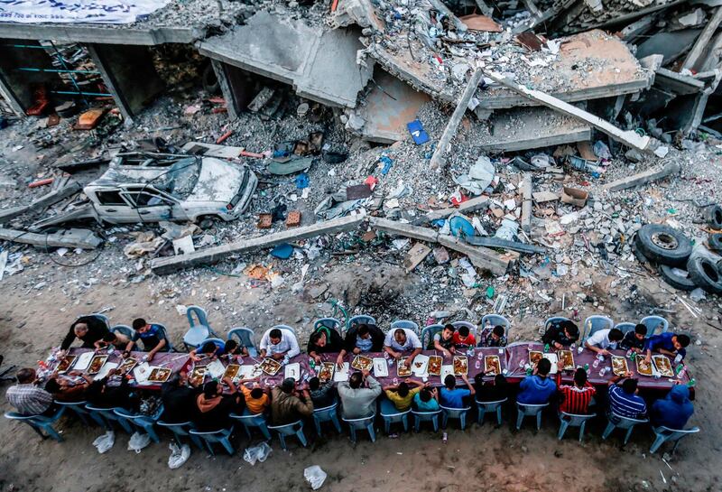 Palestinian families break their fast next to a destroyed building during recent confrontations between Hamas and Israel in the Gaza Strip.  AFP