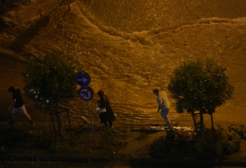 People walk next to floods in Basaksehir. AP