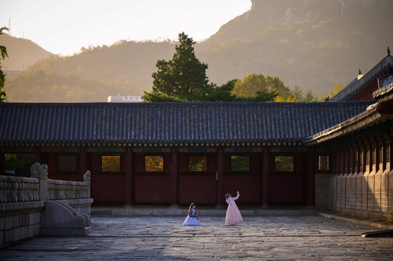 Visitors wearing traditional Korean hanbok dress pose for photos at Gyeongbokgung palace in Seoul. AFP