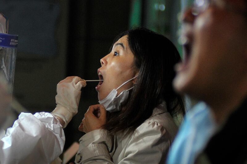 A medic takes a swab from a woman as residents test for Covid-19 near a residential area in Qingdao in east China's Shandong province. AP Photo
