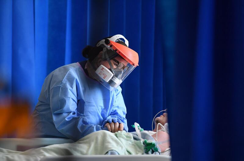 TOPSHOT - A member of the clinical staff wears personal protective equipment (PPE) as she cares for a patient at the Intensive Care unit at Royal Papworth Hospital in Cambridge, on May 5, 2020.  NHS staff wear an enhanced level of PPE in higher risk areas such as critical care to minimise the spread of infection between staff and patients. Britain's death toll from the coronavirus has topped 32,000, according to an updated official count released Tuesday, pushing the country past Italy to become the second-most impacted after the United States. / AFP / POOL / Neil HALL
