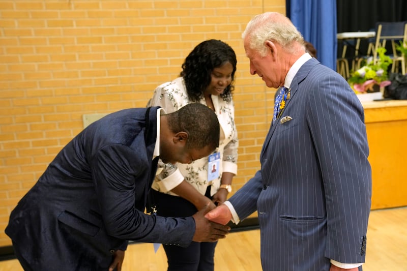 Samuel Awoyem bows to Prince Charles as his wife Toyin Awoyem looks on during a visit to the Assumption Elementary School in Ottawa, Wednesday, May 18, 2022. The Canadian Press/AP