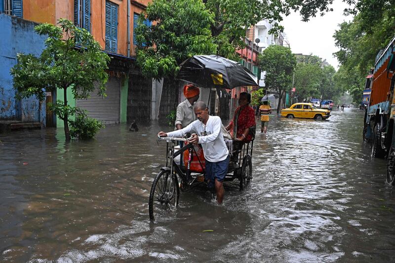 People move through a waterlogged street during rainfall in Kolkata following the landfall of Cyclone Remal in India's West Bengal state. AFP