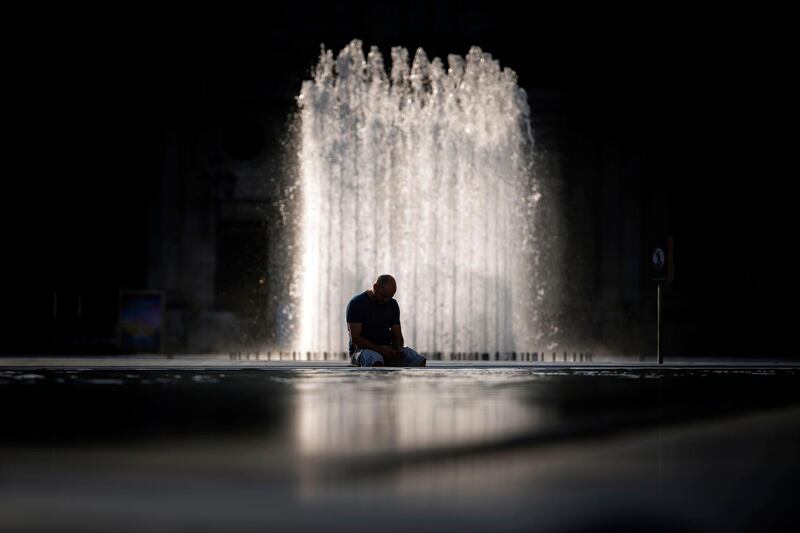 A man sits at the Louvre pyramid in Paris as a heat wave hits the French capital.  AFP