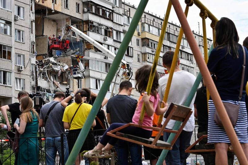 Local residents watch rescuers removing rubbles from the site of a suspected gas explosion that killed one person and ruined several flats in an apartment building, in a residential area of Kiev. AFP
