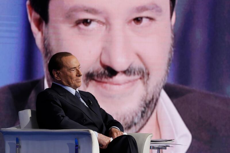 FILE - In this  Jan. 11, 2018 file photo Italian former Prime Minister and Forza Italia (Go Italy) party leader, Silvio Berlusconi, is backdropped by The League party leader Matteo Salvini during the recording of the Italian state television RAI, Porta a Porta (Door To Door) talk show in Rome. Former Premier Silvio Berlusconi is contending that 600,000 migrants in Italy are â€œreadyâ€ to commit crimes, but his foes are blaming his policies when he governed Italy for the migrant issues dominating Italyâ€™s election campaign and forming the backdrop for an anti-migrant drive-by shooting in an Italian town. (AP Photo/Andrew Medichini)