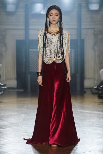 A rich red velvet dress with a bodice of draped rows of pearls is inspired by Moroccan brides