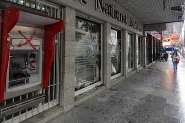 A woman walks past a bank, with windows damaged by anti-government protesters, in the capital Beirut. Debt-ridden Lebanon is facing its most serious economic crisis since the end of the 1975-1990 civil war. AFP