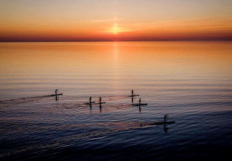 Paddle boarders tour the calm Baltic Sea in Timmendorfer Strand, northern Germany, as the sun rises on a cold spring morning. AP