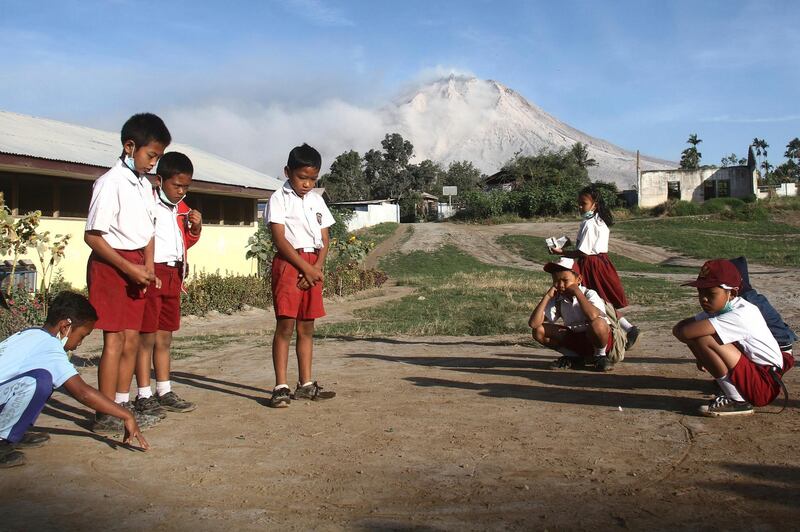 Students play before the start of their class as Mount Sinabung is seen in the background, at an elementary school in Beganding, North Sumatra. Ahmad Putra / AP Photo