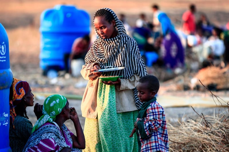 An Ethiopian migrant who fled intense fighting in their homeland of Tigray, speaks to a fellow refugee at the border reception centre of Hamdiyet, in the eastern Sudanese state of Kasala.  AFP