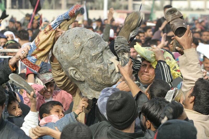 Iraqi Shiite Muslim men beat a bust of ousted president Saddam Hussein following Friday noon prayers in Sadr City, a predominately Shiite suburb of Baghdad 26 December 2003. A Shiite cleric called Friday for an Iraqi boycott of French products in protest at France's decision to ban Islamic headscarves and other religious insignia from schools. The cast head of Saddam is from a statue that was taken down months ago in Baghdad.  AFP PHOTO/Ahmad AL-RUBAYE / AFP PHOTO / AHMAD AL-RUBAYE