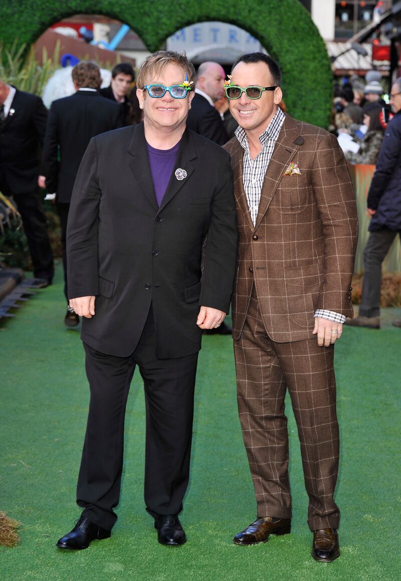 Elton John, in a black suit, purple T-shirt and glittering glasses, and David Furnish attend the premiere of 'Gnomeo And Juliet' at the Odeon Leicester Square on January 30, 2011 in London, England. Getty Images