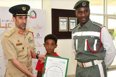 Mustafa Awad Yehia, right, with his young son, centre, was promoted following the incident. Dubai Police