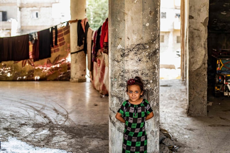 A Syrian girl, displaced with her family from Deir Ezzor, looks at the camera inside the damaged building where she is living in Syria's northern city of Raqqa.