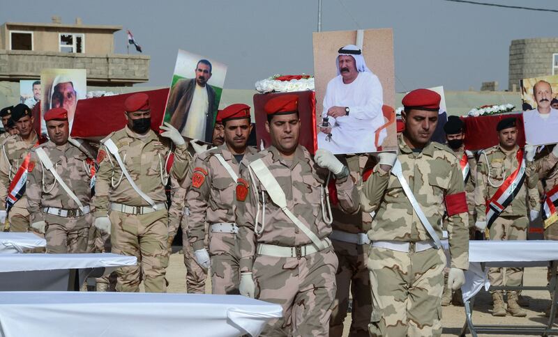 Iraqi soldiers carry coffins during a mass funeral for Yazidi victims of the ISIS genocide.  AFP