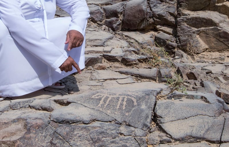 Sharjah, United Arab Emirates-  Abdullah Khilfan Al Naqbi showing what looks to be an ancient drawings carved on a rock at Al Nahwa Village in Sharjah.  Leslie Pableo for The National for Ruba Haza