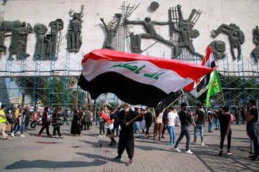 A protester waves a large Iraqi flag in Tahrir Square during a demonstration calling for the government to resign, in Baghdad, Iraq on November 15, 2020. AP