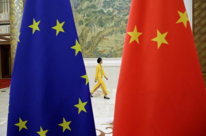 An attendant walks past flags of EU and China ahead of the EU-China High-level Economic Dialogue at Diaoyutai State Guesthouse in Beijing, China June 25, 2018. REUTERS/Jason Lee