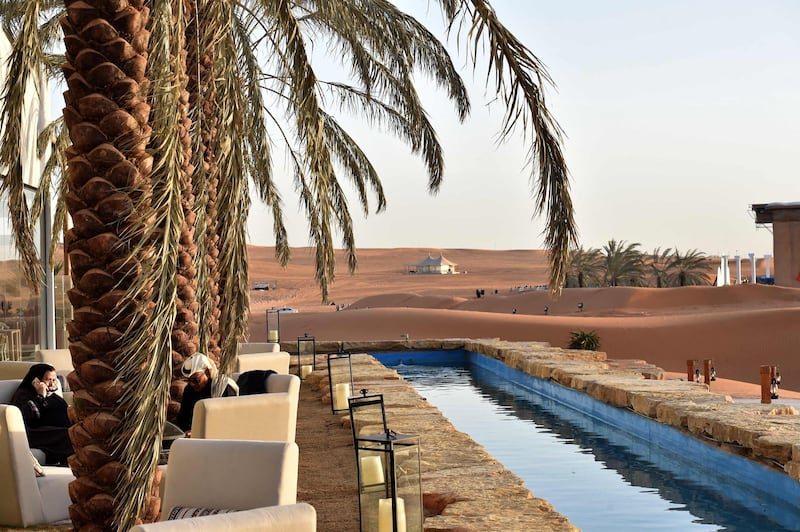 People relax in a lounge area by a water canal at the "Riyadh Oasis." AFP