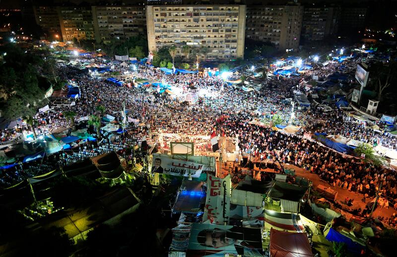 Supporters of Egypt's ousted President Mohammed Morsi gather for prayers at Nasr City, where protesters have installed a camp and hold daily rallies, in Cairo, Egypt, Sunday, July 28, 2013. Escalating the confrontation after clashes that left more than 80 supporters of Egypt's ousted Islamist president dead, the interim government moved Sunday toward dismantling two pro-Mohammed Morsi sit-in camps, accusing protesters of "terrorism" and vowing to deal with them decisively.  The Arabic on the poster at right reads "El-Sissi traitor, murder."  The writing at center reads "The people of the nation against the coup." (AP Photo/Hassan Ammar) *** Local Caption ***  Mideast Egypt.JPEG-03e4d.jpg