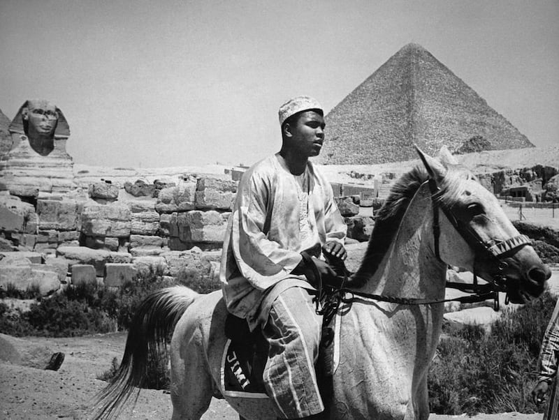 World heavyweight boxing champion Muhammad Ali, who died on June 3, 2016 at the age of 74, seen here wearing tradional ghanaian costume as he rides near the Pyramids of Gizeh, near Cairo in 1964. Ali was on a one-month trip to Africa and Middle East at that time and announced in February  28, 1964 that he was member of the Nation of Islam and converted to muslim faith. AFP Photo