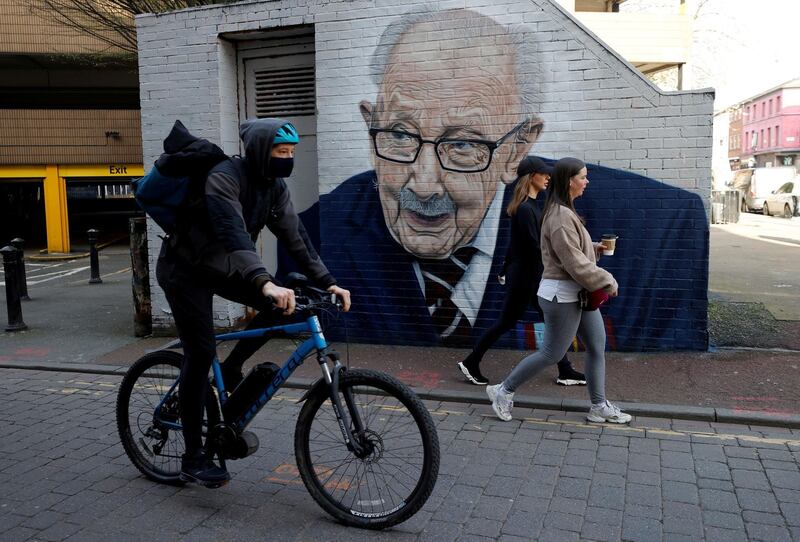 People walk past a new mural of British veteran and fundraiser Captain Tom Moore by artist Akse P19 in Manchester. Reuters