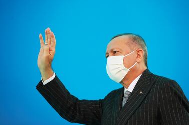 Turkey's President Recep Tayyip Erdogan, wearing a mask to help protect against the spread of coronavirus, waves toward his ruling Justice and Development Party members at a soccer stadium, in Kahramanmaras, Turkey, Saturday, Nov. 7, 2020. (Turkish Presidency via AP, Pool)