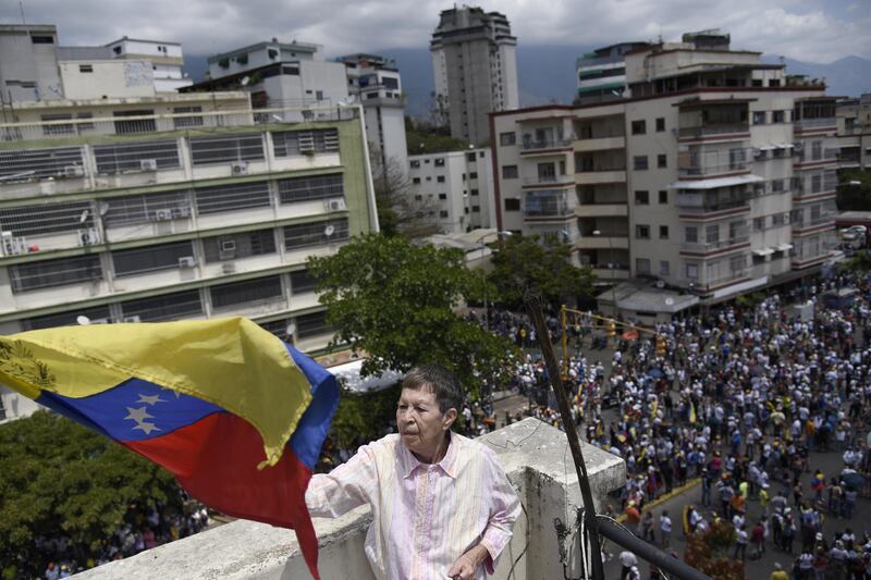 A person waves a Venezuelan flag as demonstrators gather during an anti-government protest in Caracas, Venezuela. Bloomberg