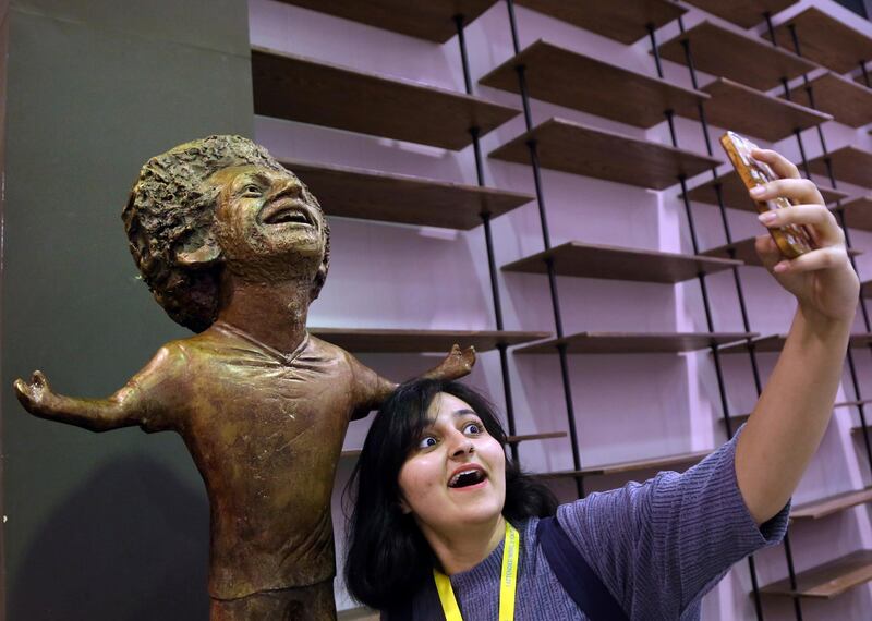 A participant at an international youth gathering poses for a selfie with a bronze statue of Liverpool striker Mohammed Salah in Sharm El Sheikh, Egypt. AP Photo