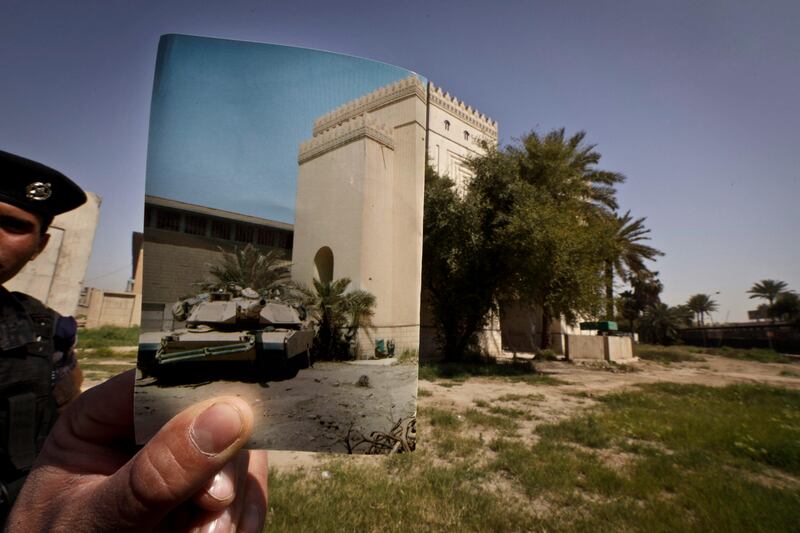 In this Wednesday, March 13, 2013 photo, Iraqi policeman Ahmed Naji stands on the grounds of the Iraqi National Museum at the site of an Associated Press photograph by Murad Sezer showing a U.S. Army tank parked outside the Iraqi National Museum in Baghdad on Tuesday, May 6, 2003. Tens of thousands of artifacts chronicling some 7,000 years of civilization in Mesopotamia are believed to have been looted from Iraq in the chaos which followed the the US-led invasion in 2003. Despite international efforts to track items down, fewer than half of the artifacts have so far been retrieved. (AP Photo/Maya Alleruzzo) *** Local Caption ***  Mideast Iraq On This Site.JPEG-0b355.jpg