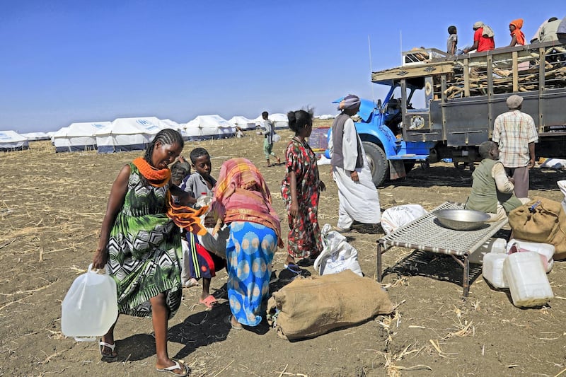 Ethiopian refugees, who fled the Tigray conflict, gather their belongings upon their arrival at the Tenedba camp in Mafaza, eastern Sudan on January 8, 2021, after being transported from the reception center. (Photo by ASHRAF SHAZLY / AFP)