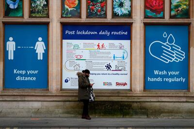 A pedestrian walks past hoarding with advice on how to stay safe during the Covid-19 pandemic on the high street in Slough, west of London, on January 18, 2021. Britain on January 18 extended its coronavirus vaccination campaign to people over the age of 70, and new tougher restrictions for all arrivals to the country came into force. Since the innoculation campaign began on December 8, more than 3.8 million people have received a first dose of vaccine against the virus that has infected 3.4 million people in the UK and claimed more than 89,000 lives.  / AFP / Adrian DENNIS
