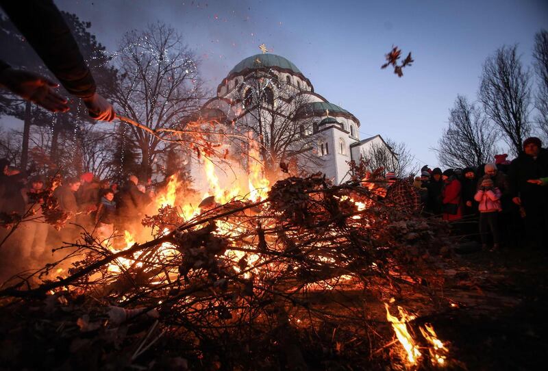 People gather for the annual bonfire outside the Saint Sava church during the ceremonial burning of dried oak branches, symbolising the Yule log during the Orthodox Christmas eve celebrations in Belgrade, AFP
