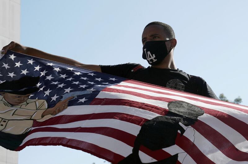 A demonstrator waves a U.S. flag painted with a police officer aiming a gun at a Black man, at a protest against racial injustice and the fatal Gardena shooting of 18 year-old security guard Andres Guardado by a Los Angeles County Sheriff’s Department deputy, in Compton, California, U.S. REUTERS