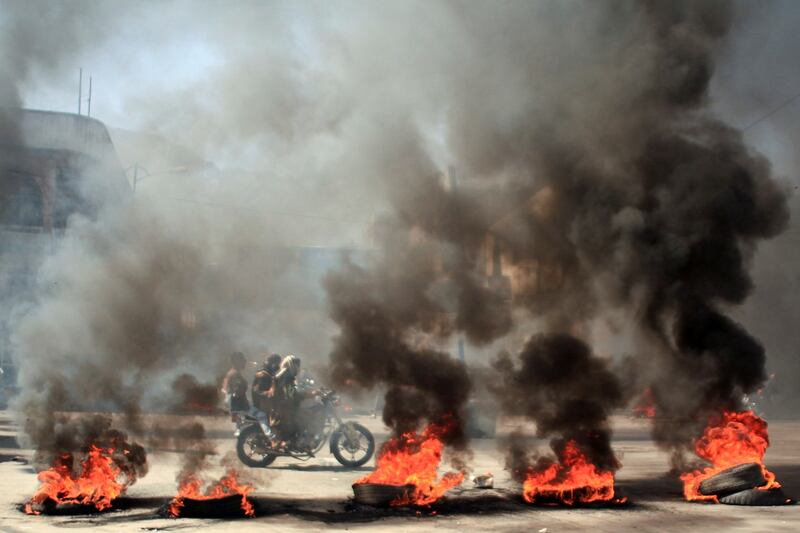 People ride a motorcycle past burning tires during protests against the deteriorating economic situation and the devaluation of the local currency, in Taiz, Yemen, on September 27, 2021.  Reuters.