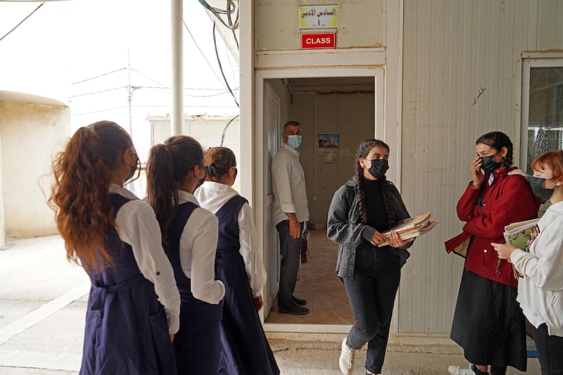 Girls receive text books before heading to class on the first day of school at a Yazidi displacement camp in the Sharya area near the city of Dohuk in Iraqi Kurdistan.  AFP