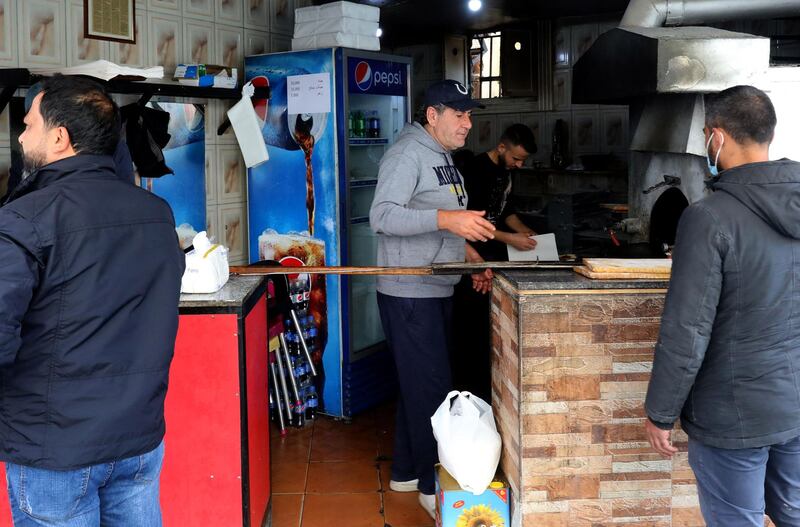 Abu Shadi serves customers at his bakery. AFP
