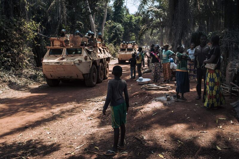 Families displaced by conflict watch as a convoy of UN peacekeepers passes by on the outskirts of Bangassou. AFP