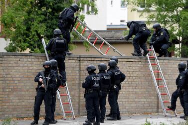 Police officers climb over the cemetery wall of a Synagogue after a shooting in Halle, Germany. EPA