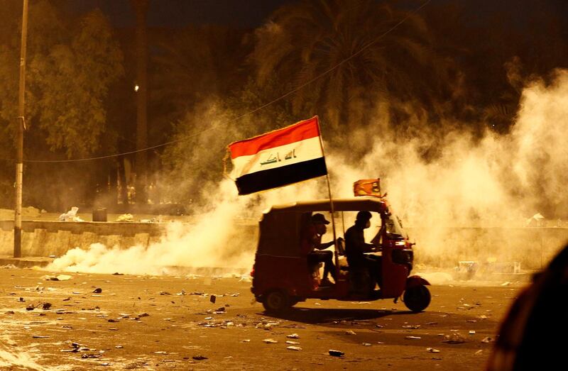 A tuk-tuk drives away from tear gas fired by Iraqi security forces during a protest over corruption, lack of jobs, and poor services, in Baghdad, Iraq October 26, 2019. REUTERS/Thaier Al-Sudani
