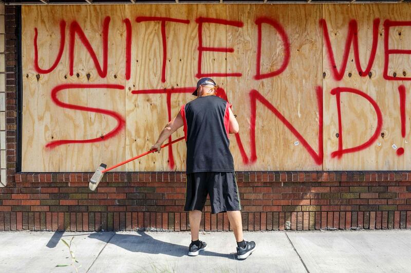 Tom Bernard, cleans the front of his damaged shop on June 1, 2020 in Minneapolis, Minnesota, after protests for George Floyd, an unarmed black man who died after being pinned to the ground by a Minneapolis police officer in Minneapolis, Minnesota. AFP