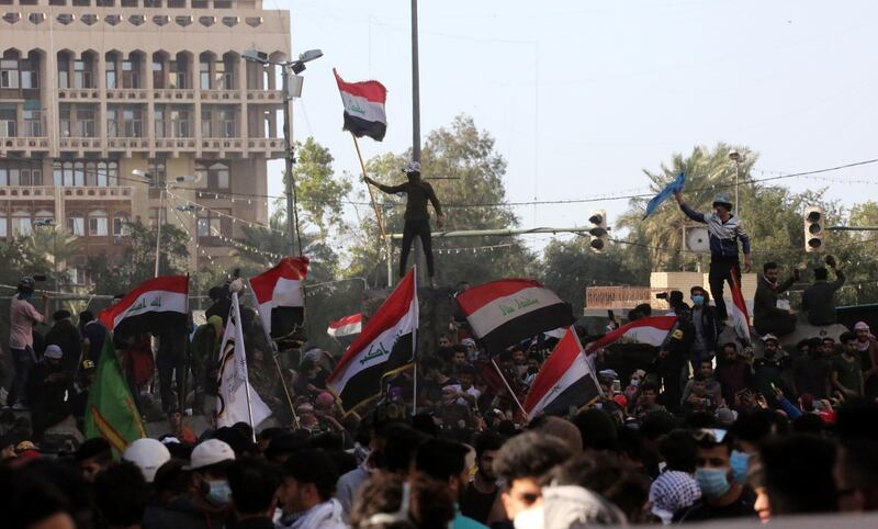 Iraqi protesters carry the Iraqi national flag as they gather on concreat blocks which were used by security forces to close the Al-Khilani square in central Baghdad, Iraq.  EPA