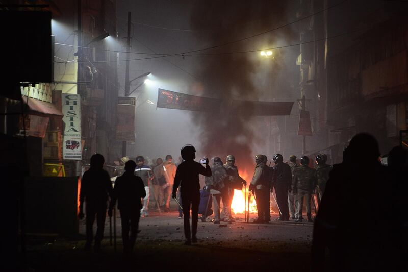 Firefighters and police personnel stand next to burning objects set on fire during demonstrations against India's new citizenship law in Kanpur. AFP