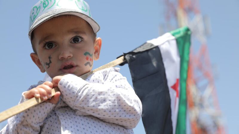 A Syrian child holds the Syrian opposition factions' flag during a protest against the presidential elections, in Idlib. EPA